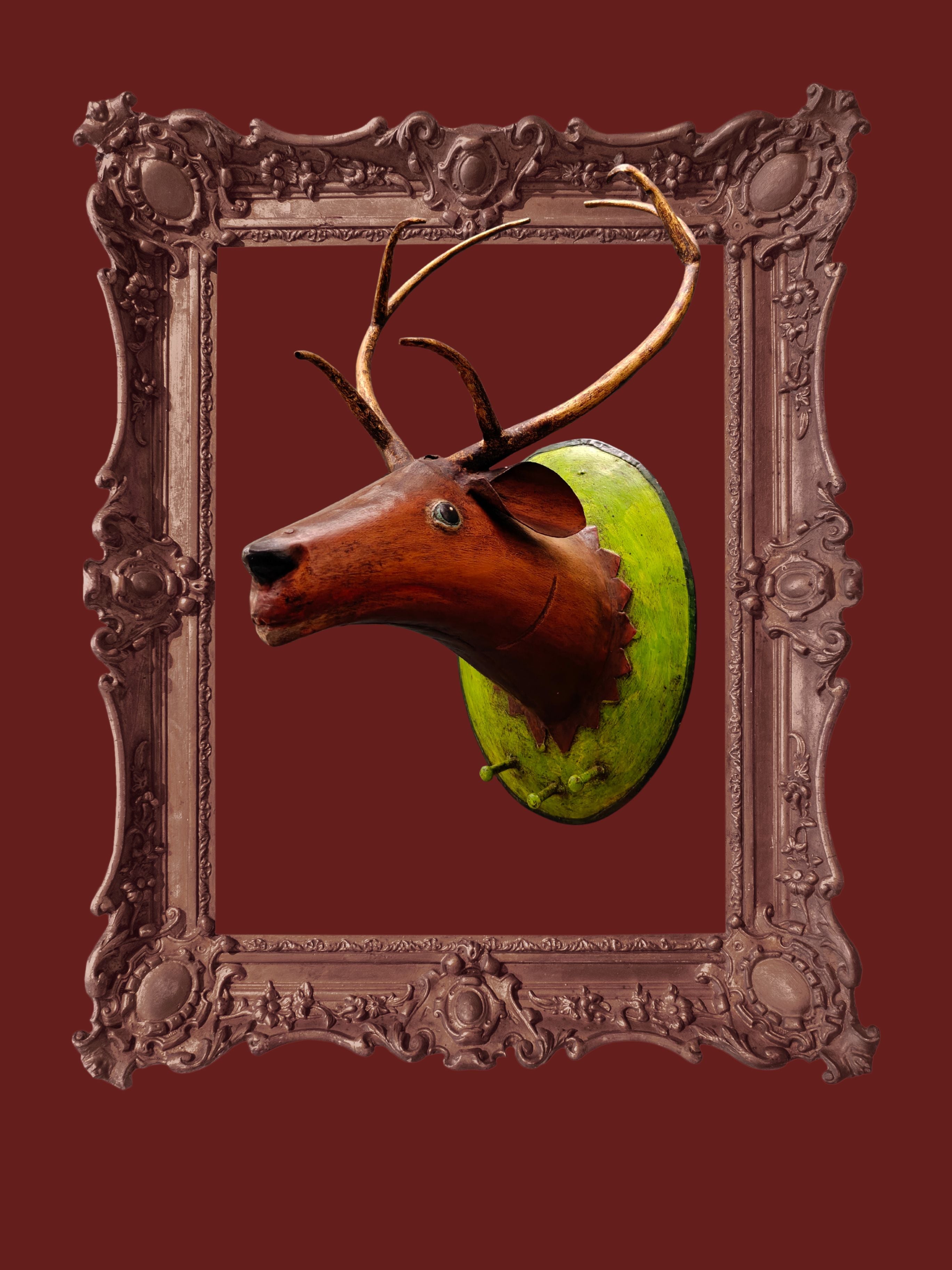 Decorative deer head with antlers in an ornate frame on a red background