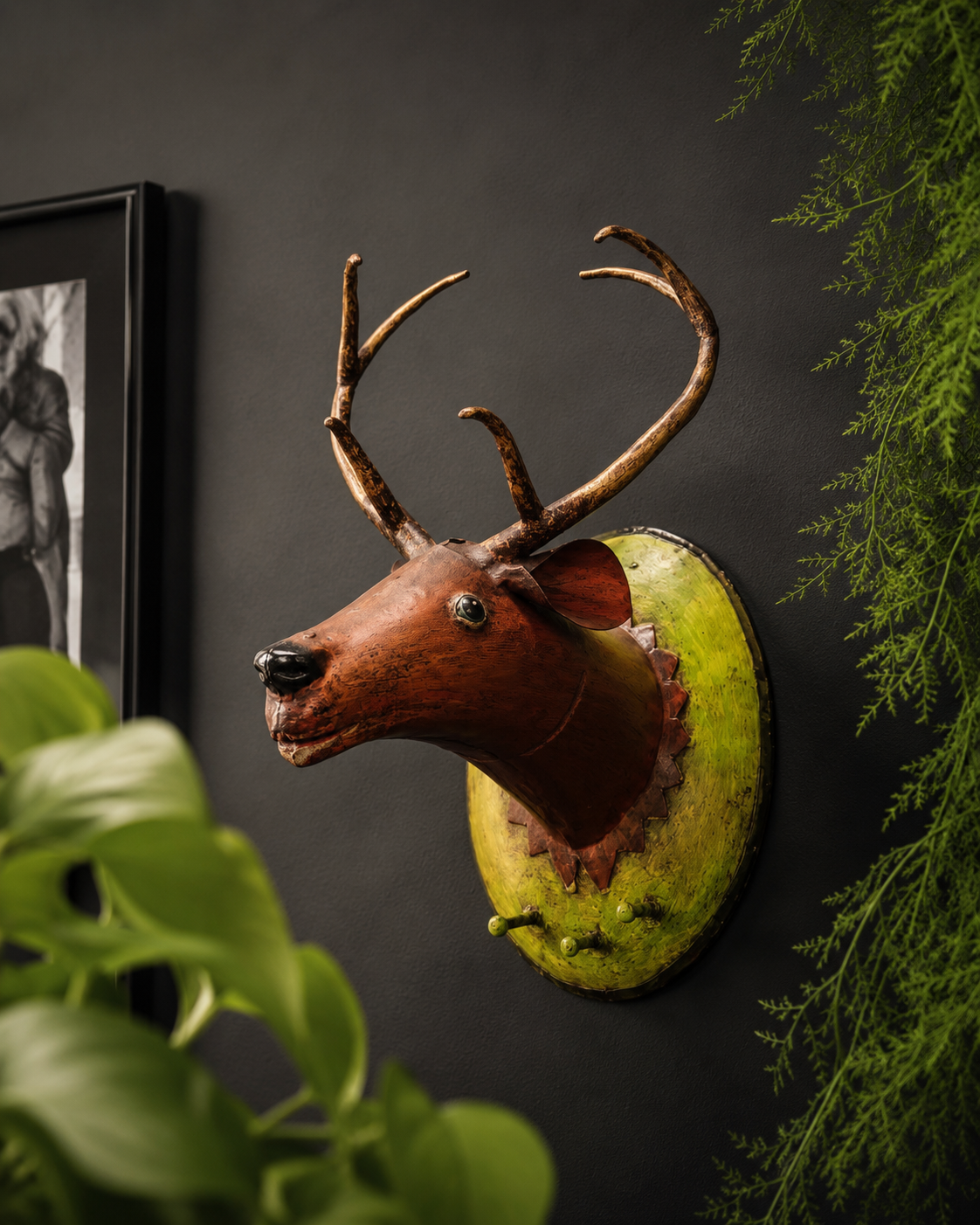 Decorative deer head mount on a dark wall with greenery